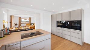 A modern kitchen with a central island, built-in appliances, and a dining area with a sofa and table. - Enjoy the new vacation apartment in a prime location with a 10% weekly discount (Bad Kohlgrub)