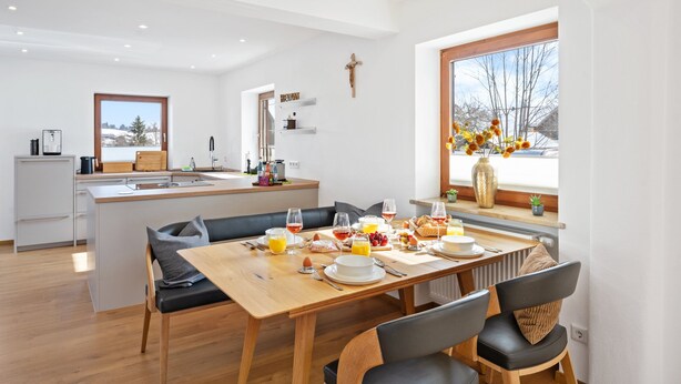 A modern kitchen with a dining area, a large window with a view, and a cross on the wall. - Enjoy the new vacation apartment in a prime location with a 10% weekly discount (Bad Kohlgrub)