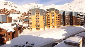 En snötäckt bergsstad med både moderna och traditionella byggnader, inklusive ett framstående hotell med flera våningar och balkonger.