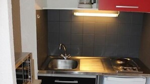 Ett kompakt kök med en diskho, en spis och en kaffebryggare på bänkskivan.