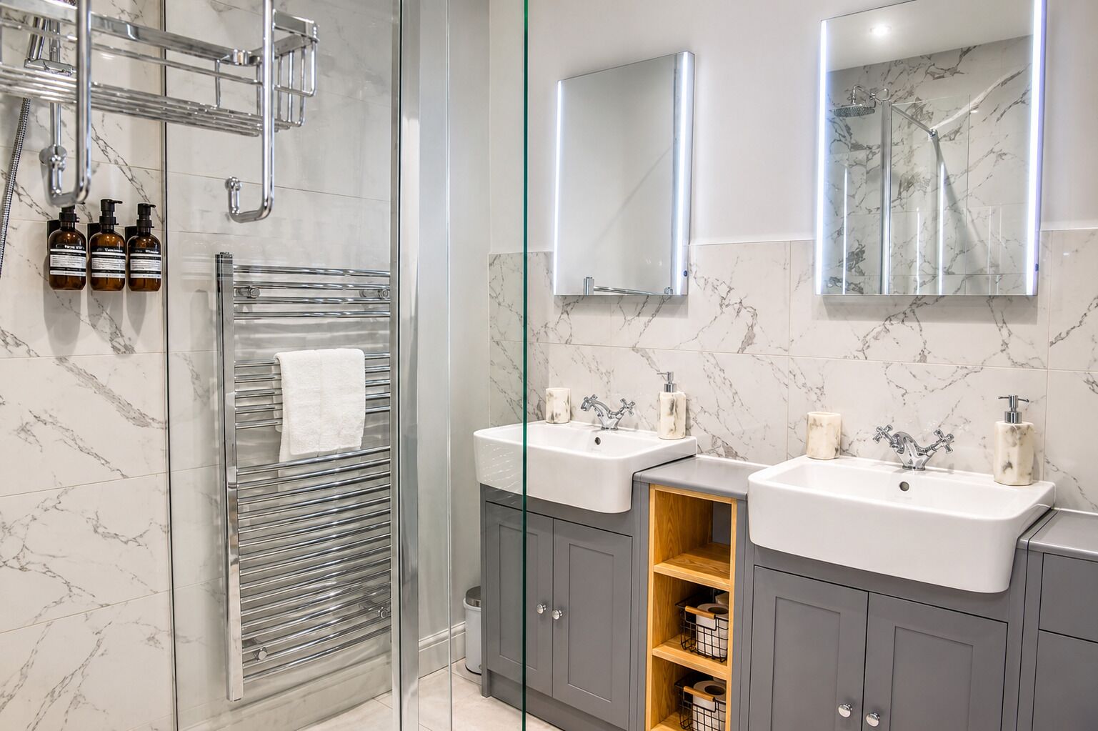 A modern bathroom with two sinks, a glass shower enclosure, and marble-patterned walls.