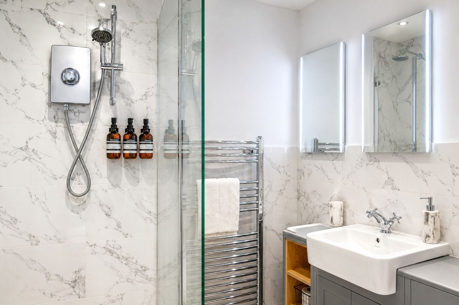 Un baño moderno con cabina de ducha de vidrio, lavamanos integrado y pared revestida de mármol.