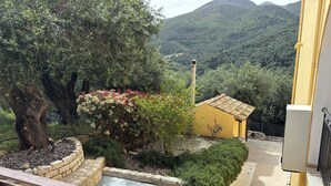 Une cour avec une fontaine en pierre, un banc en bois et un bâtiment jaune doté d’un toit en tuiles.