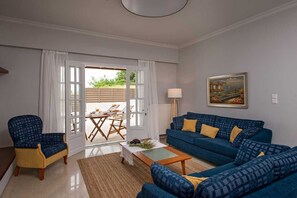 Un saló amb un sofà blau, un butac armchair groc, una taula de centre i un quadre a la paret.