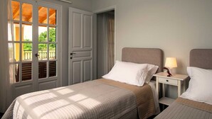 Une chambre d’hôtel avec un lit, une table de chevet et une fenêtre donnant sur un paysage verdoyant.