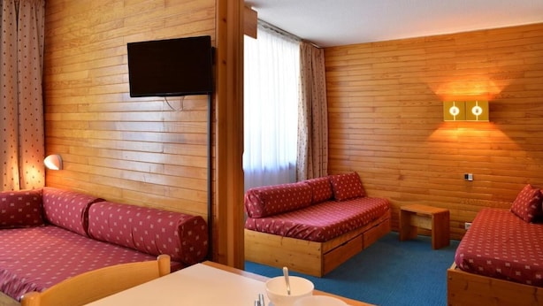 A cozy room with wooden walls, a flat-screen TV mounted on the wall, and a table with a bowl and spoon.