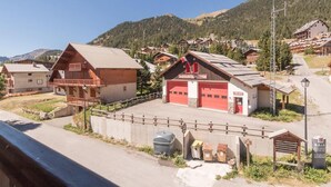 A mountain lodge with a red garage and wooden buildings, surrounded by hills and clear skies. - 250m from ski slopes, 1st floor, view village, balcony, parking, tv, 30m², Montgenèvre (Montgenèvre)