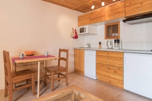 A compact kitchen with wooden cabinets, a white dishwasher, and a microwave. - 350m from resort center, 1st floor, view ski slopes, balcony, tv, 28m², Montgenèvre (Montgenèvre)