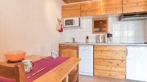A kitchen with wooden cabinets, a microwave, a sink, and a dishwasher. - 250m from ski slopes, 1st floor, view ski slopes, balcony, tv, 28m², Montgenèvre (Montgenèvre)