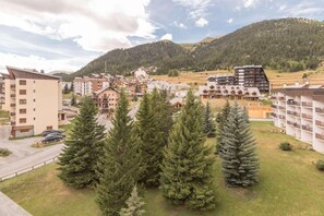 Zona residencial con edificios de varios pisos, estacionamiento y montañas al fondo.