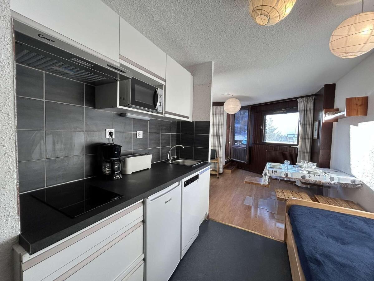 A compact kitchen with a microwave, coffee maker, and dishwasher. There is a dining area with a table and chairs, and a window providing natural light.