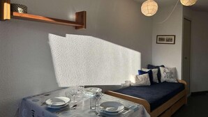 A room with a bed, a table set for dining, and two hanging light fixtures. - 220m from resort center, 5th floor, view village, balcony, parking, tv, 35m², Montgenèvre (Montgenèvre)