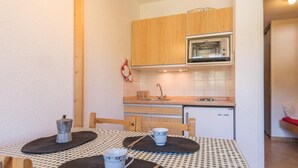A compact kitchen with wooden cabinets, a built-in oven, and a small sink. - 2nd floor, view mountain, balcony, parking, tv, 20m², Montgenèvre (Montgenèvre)