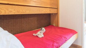 A small, single-bed room with a wooden headboard and a red mattress. - 2nd floor, view mountain, balcony, parking, tv, 20m², Montgenèvre (Montgenèvre)