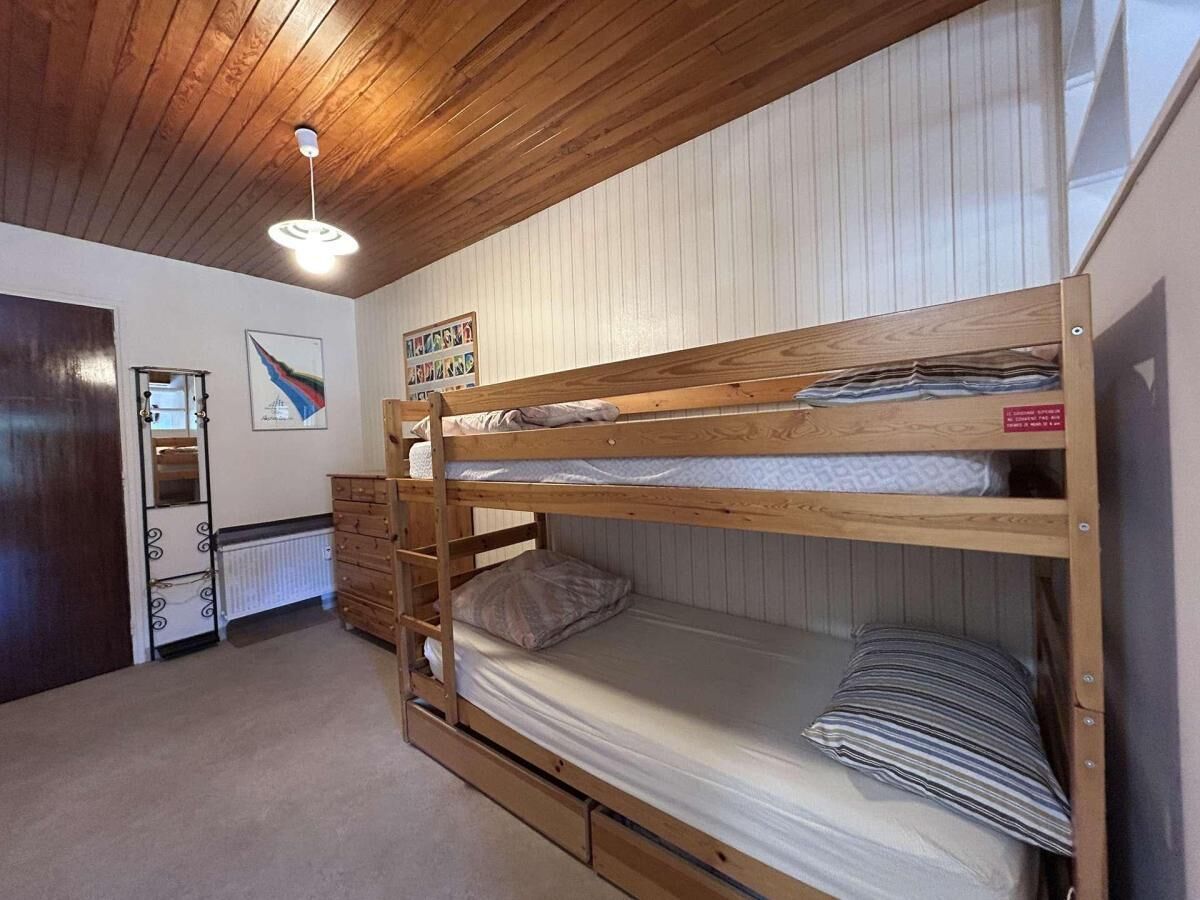 A bunk bed room with a wooden ceiling, a dresser, and a radiator.