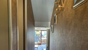 Un pasillo con suelo de madera, una escalera y vista a un comedor con mesa y sillas.