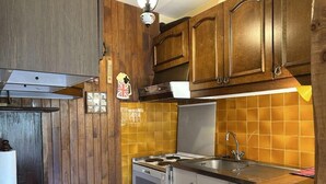 Una cocina compacta con armarios de madera, estufa y lavamanos.