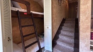 Un dormitorio con literas, una puerta y una escalera.