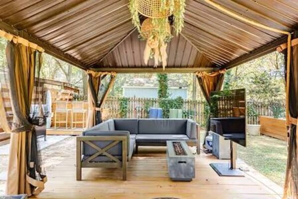 Un espace extérieur aménagé, abrité et doté d’un canapé, d’une table basse et d’un barbecue.