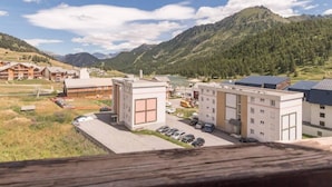 A hotel with a parking lot, buildings, and a mountainous backdrop.