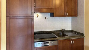 A kitchen with wooden cabinets, a built-in oven, a dishwasher, and a granite countertop.