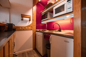 A compact kitchen with wooden cabinets, a sink, a microwave, and a dishwasher. - 7th floor, view valley, balcony, tv, 40m², Les Arcs (Les Arcs)