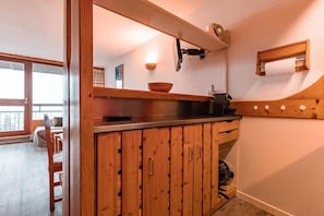 Une cuisine avec des meubles de rangement en bois, un évier et une fenêtre donnant sur un balcon.