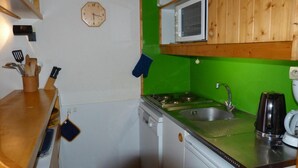 A compact kitchen with a microwave, sink, and stove. There is a clock on the wall and a wooden cabinet above the stove. - Ski-in/ski-out & foot of the slopes, 2nd floor, view mountain, balcony, tv, 35m², Les Arcs (Les Arcs)