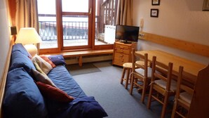 A cozy room with a sofa, a wooden table with chairs, a television, and a balcony with a railing. - Ski-in/ski-out & foot of the slopes, 2nd floor, view mountain, balcony, tv, 35m², Les Arcs (Les Arcs)