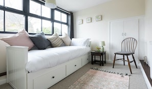 A bedroom with a white sofa, a small side table with a lamp, a wooden chair, and a radiator. - Bieldside Cottage Ollerton (Ollerton)