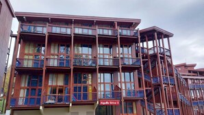 Een meerlaags gebouw met balkons en een bord waarop staat: Aiguille Grive II.