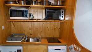 Uma cozinha compacta com micro-ondas, forno, pia e máquina de lavar louça.