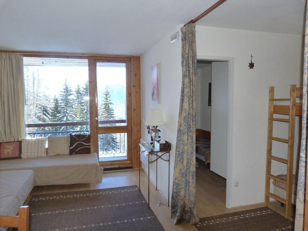 Un dormitorio con cama, escritorio y vista a árboles por una ventana.