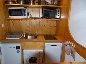 A compact kitchen with a microwave, oven, sink, and dishwasher.
