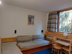 A compact room with a sofa bed, a small table, and a window with curtains. - 9th floor, view firs, tv, 13m², Les Arcs (Les Arcs)