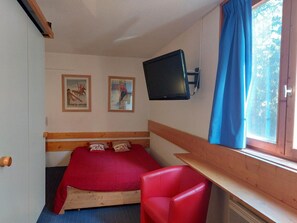 A bedroom with a bed, a red chair, a mounted TV, and two framed pictures on the wall. - 9th floor, view firs, tv, 17m², Les Arcs (Les Arcs)