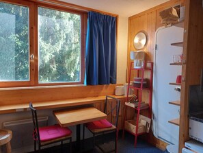 A cozy cabin interior with a wooden bench, a table, a chair, a shelf with items, and a window with curtains. - 9th floor, view firs, tv, 17m², Les Arcs (Les Arcs)