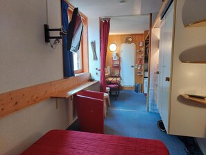 A compact room with a bed, a small table, and a chair. There is a door leading to another room with a bed and a window. - 9th floor, view firs, tv, 17m², Les Arcs (Les Arcs)