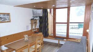 Una habitación acogedora con una mesa y sillas de madera, un banco y un sofá.