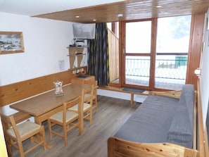 Ein gemütliches Zimmer mit Holztisch und -stühlen, einer Bank und einem Sofa.