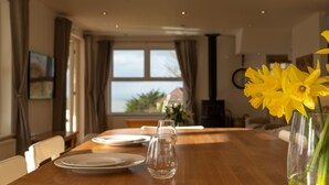 Una mesa de comedor dispuesta con platos, una copa y un jarrón con flores amarillas.