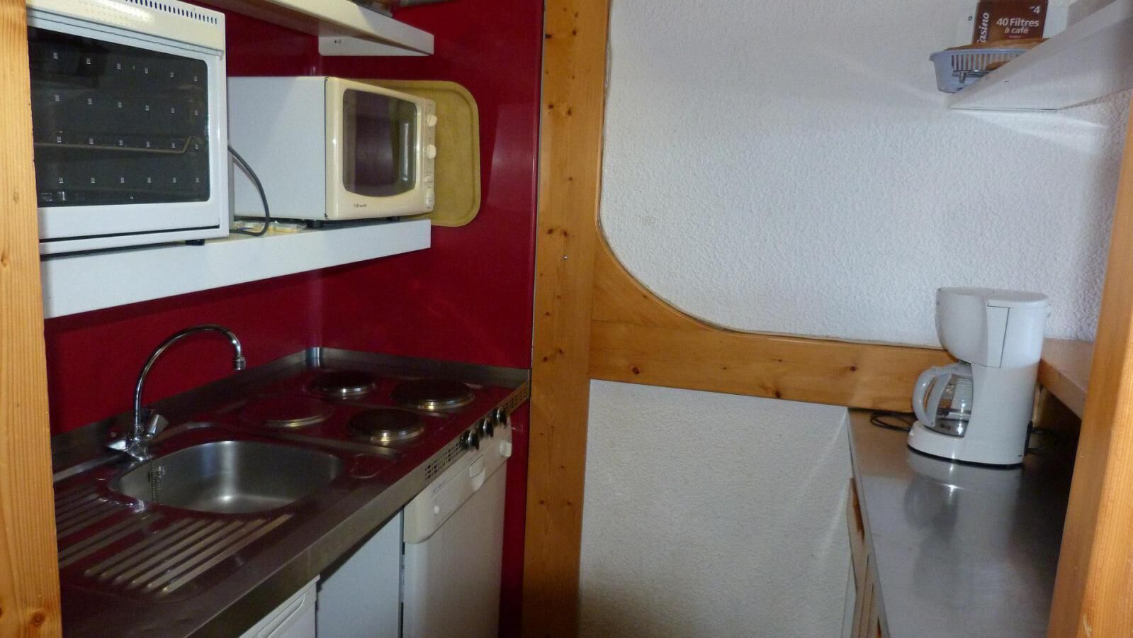 Eine kleine Küchenzeile mit Mikrowelle, Herd, Spüle und Kaffeemaschine.