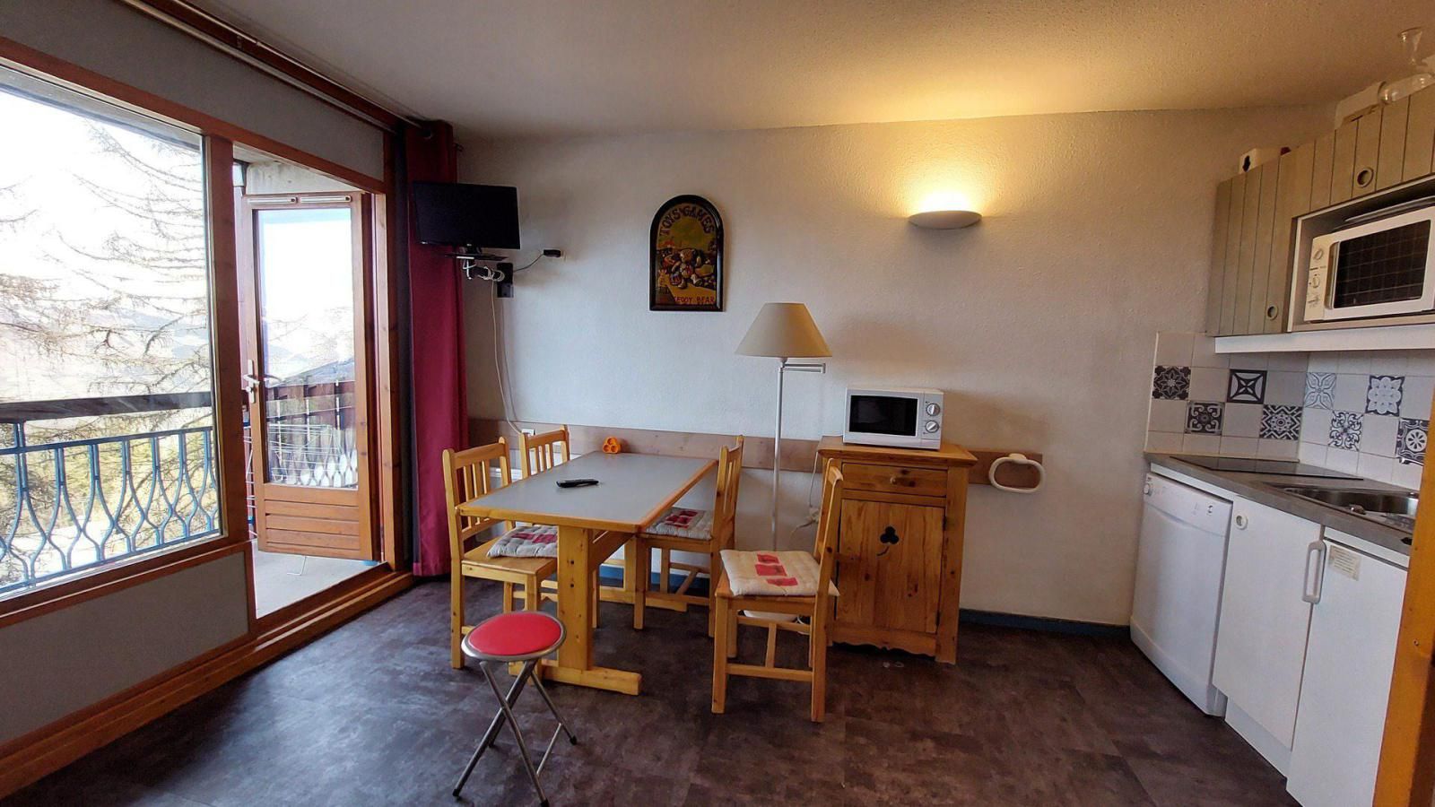 A compact kitchen with a dining table, chairs, a microwave, and a small cabinet.