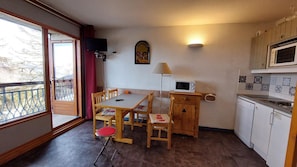A compact kitchen with a dining table, chairs, a microwave, and a small cabinet.