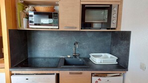 A compact kitchen with a black countertop, a built-in microwave, a sink, and a dishwasher. - 14th floor, view valley, terrace, tv, 54m², Les Arcs (Les Arcs)