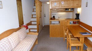 A compact living space with a wooden sofa, a dining table with benches, and a kitchenette area. - Ski-in/ski-out & foot of the slopes, 3rd floor, balcony, tv, 40m², Les Arcs (Les Arcs)