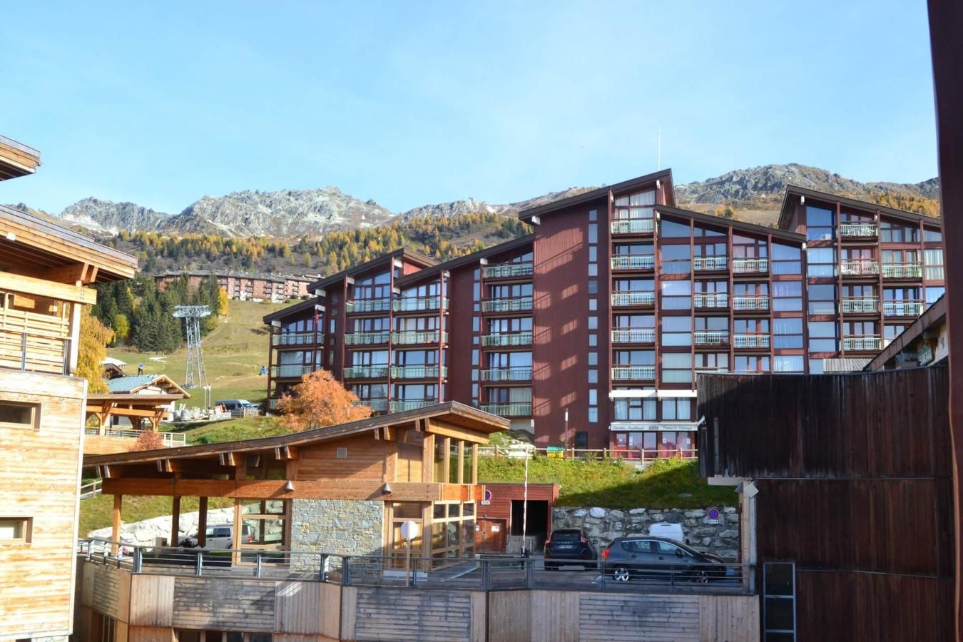 A modern hotel with multiple floors, large windows, and a view of mountains in the background.