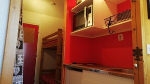 Een kleine keuken met een magnetron, een spoelbak en een klein aanrecht.