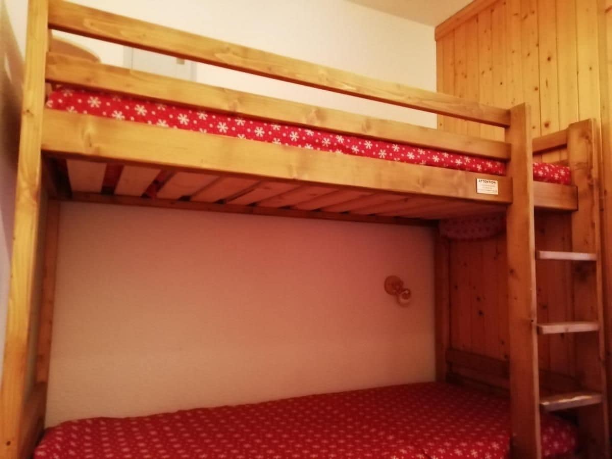 Una cama litera con un colchón rojo estampado y un cabecero de madera.