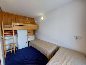 A dormitory room with bunk beds, a desk, and a chair.